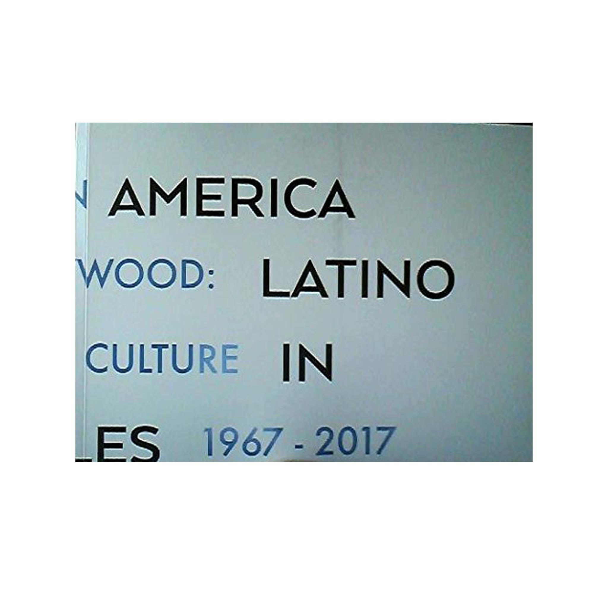 Book cover with text 'America Wood: Latino Culture in ES 1967-2017' on a light blue background
