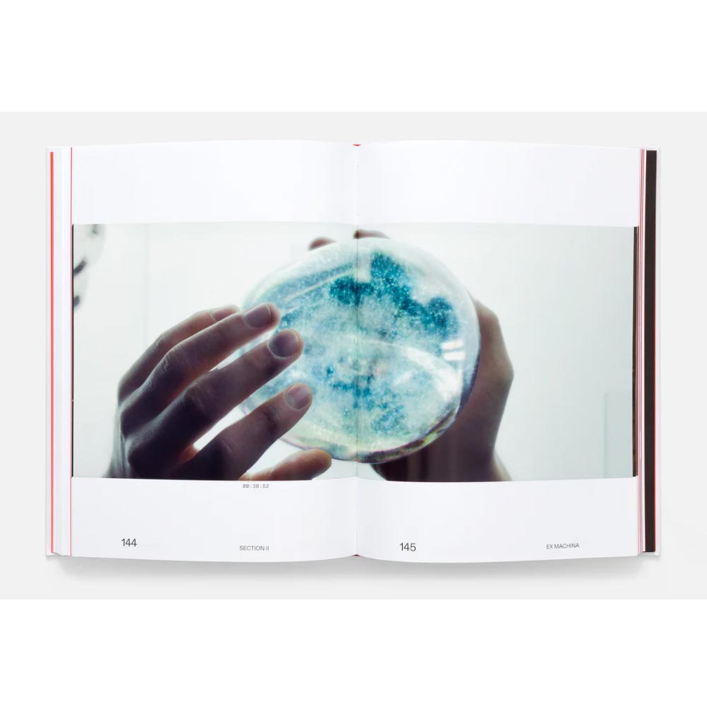 Open book showing a page with a hand holding a petri dish containing blue and white colonies.