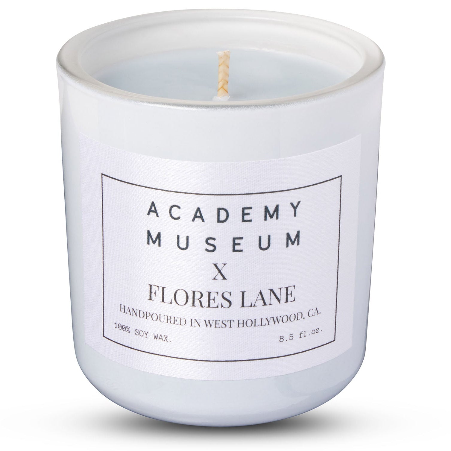 White candle with 'Academy Museum x Flores Lane' label on a white  Indulge in the LOW RESOLUTION CANDLE, an 8oz soy candle featuring leather and smoked cognac scents. 40 hours of eco-friendly luxury in a recycled glass vessel.background FLORES LANE MOVIE GENRE SCENTED CANDLE: FILM NOIR | ACADEMY MUSEUM