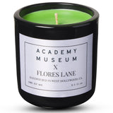 Green candle in a black container with a label on a white background FLORES LANE MOVIE GENRE CANDLES: SCI-FI MOVIE | ACADEMY MUSEUM