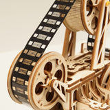 Wooden mechanical model of a film projector with film reels and film strip.