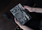 Person holding a book with a black and white cover featuring text and a face.