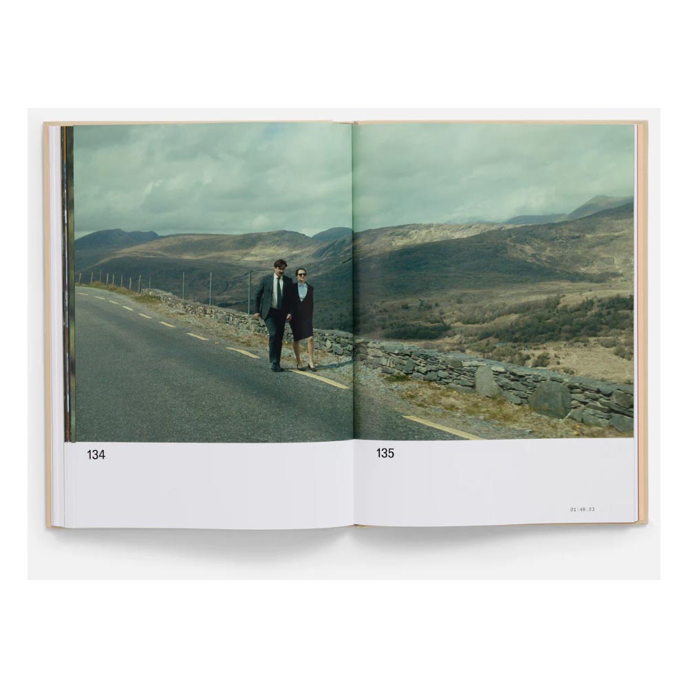 Open book showing a couple walking on a road with mountains in the background