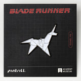 Enamel pin of a blade runner design on a Blade Runner branded card with Pinterrill and Academy Museum logos.
