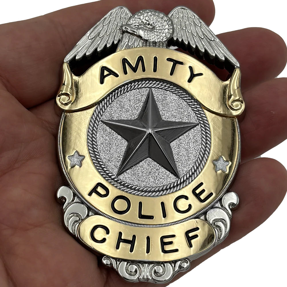 Amity Police Chief badge held in a hand from the movie JAWS (1975) for the 50th Anniversary of the film this is a limited edition officially licensed prop replica