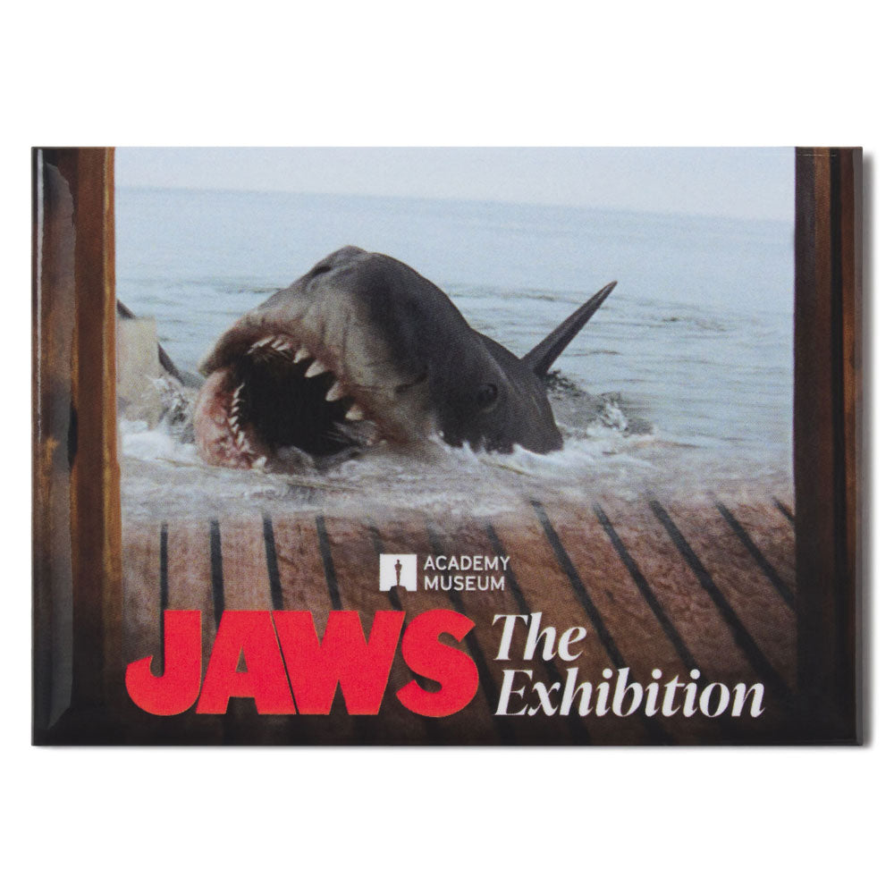 Promotional poster for 'Jaws: The Exhibition' featuring a shark emerging from water.