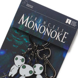 A multicharm keychain featuring Kodama from Princess Mononoke, with glow-in-the-dark enamel charms on a black nickel base, displayed on a card with the movie title.