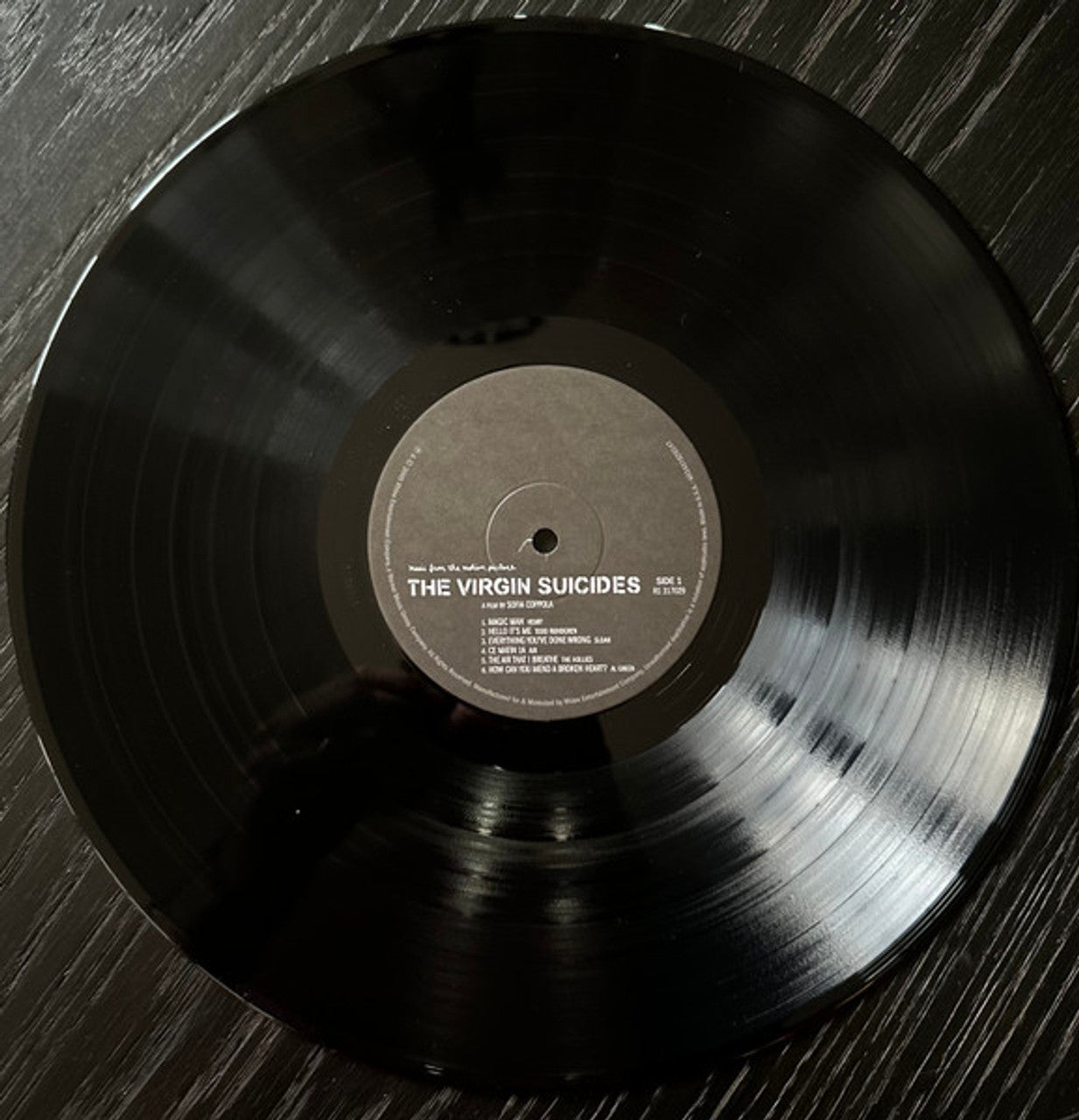 Vinyl record with 'The Virgin Suicides' album on a wooden surface