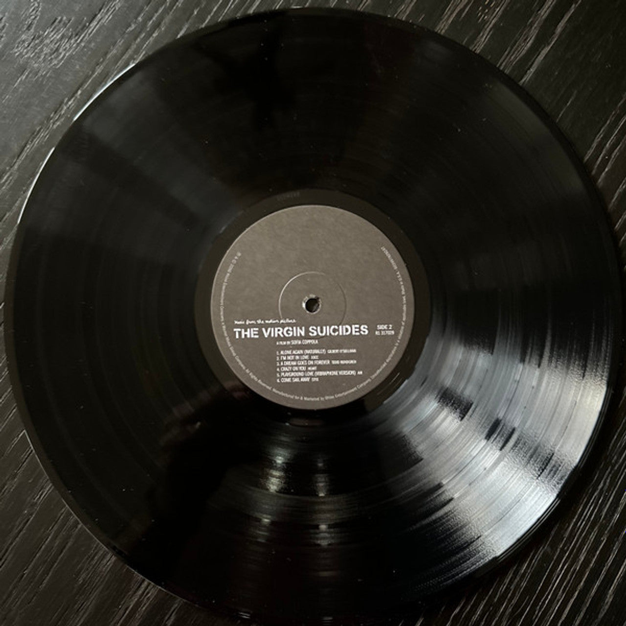 Vinyl record with 'The Virgin Suicides' on a wooden surface