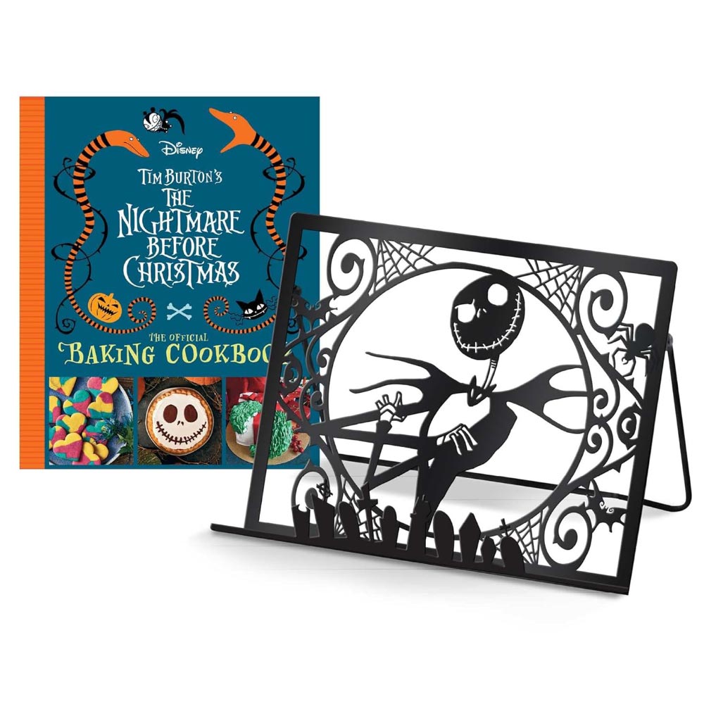 The image shows the cover of a cookbook titled 'Tim Burton's The Nightmare Before Christmas: The Official Baking Cookbook' featuring colorful illustrations of characters from the movie. There is also an exclusive metal cookbook/tablet stand with a Nightmare Before Christmas design.
