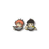 A set of two enamel pins featuring animated characters from the film Ponyo, depicting a girl with red hair and a boy with black hair, both sitting at a table.