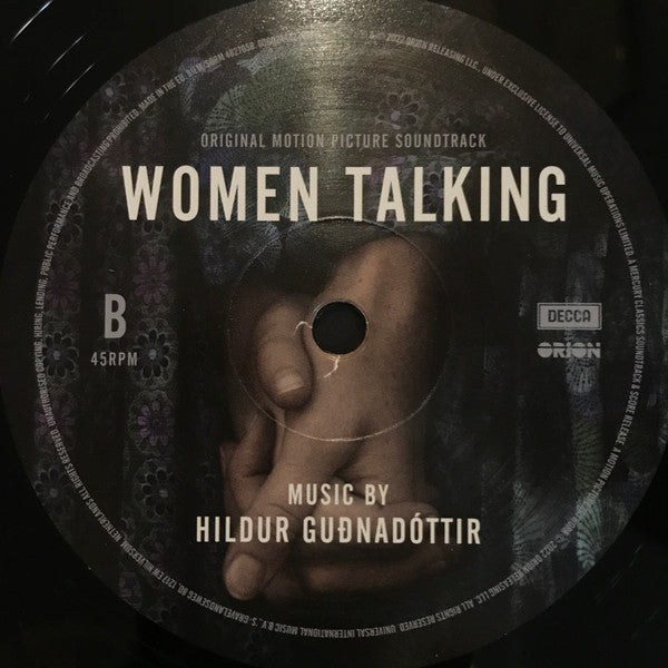 Vinyl record label for 'Women Talking' soundtrack with a hand holding an ear design.