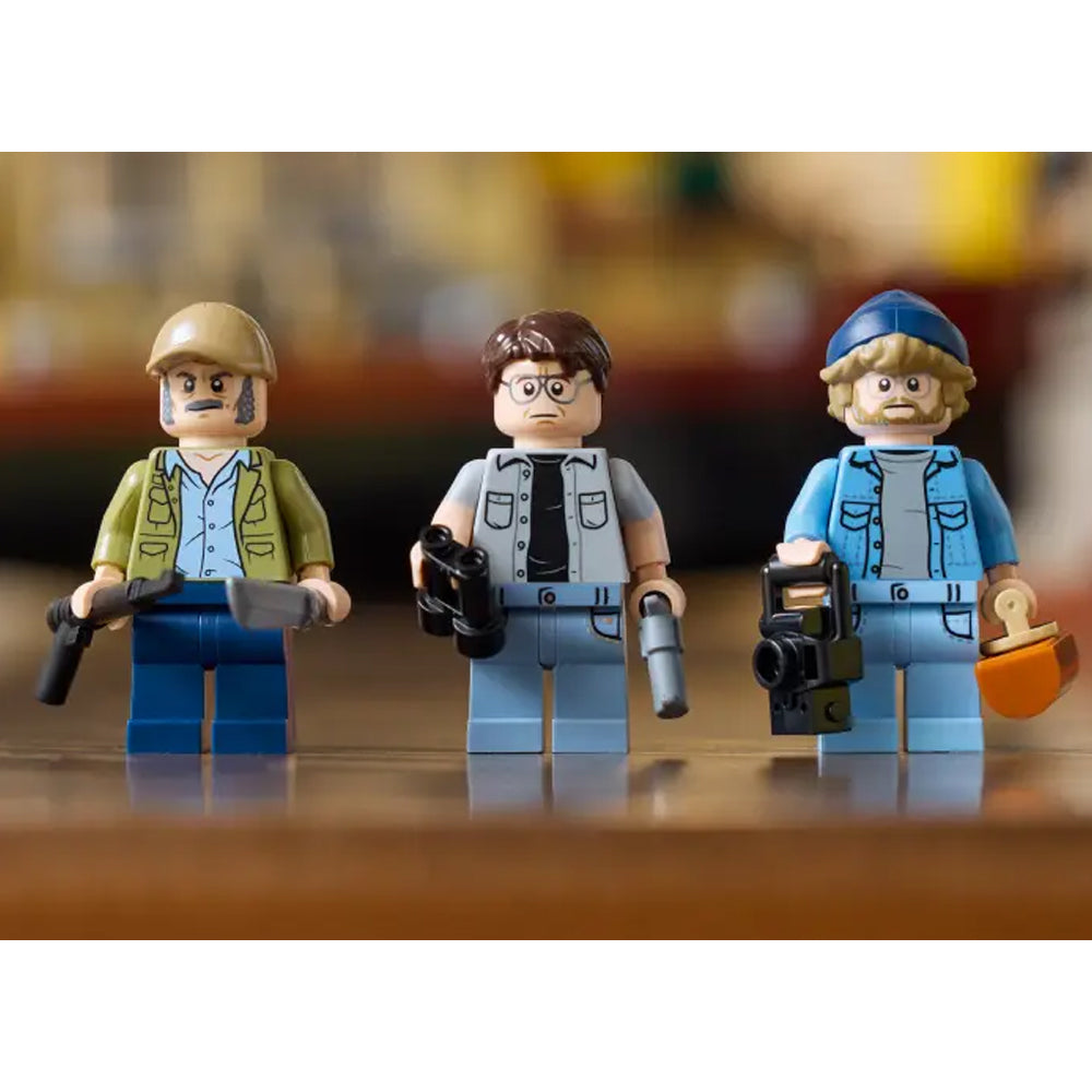 Three LEGO figures with weapons on a wooden surface Jaws (1975) 50th Anniversary Lego Set