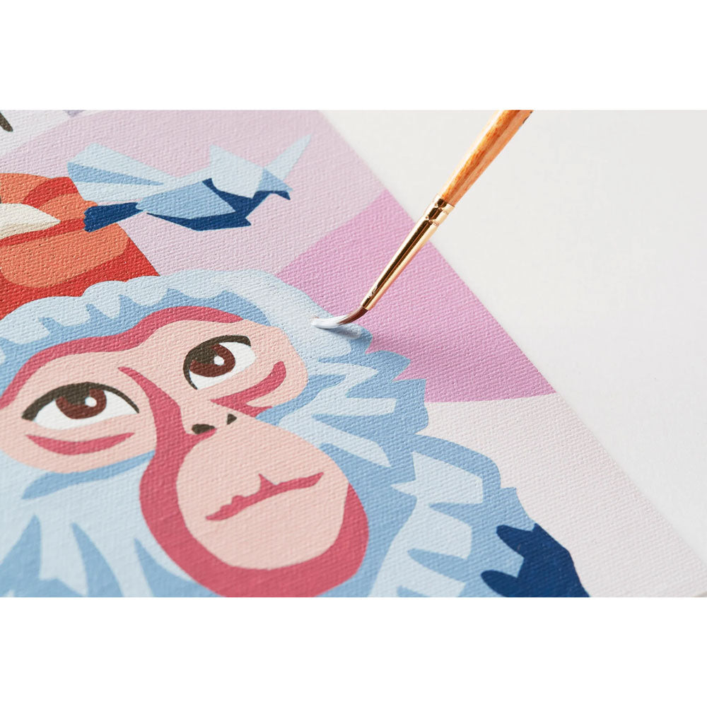 Close-up of a painting with a monkey's face and a brush applying paint.