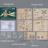 Vitascope model kit components including package box, wooden sheets, assembly instruction, accessories pieces, and roll film on a gray background.