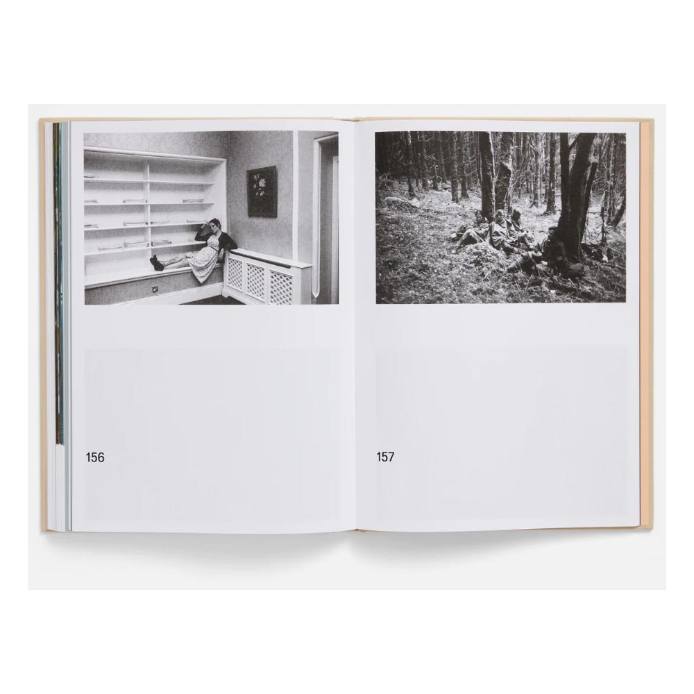Open book showing two black and white photographs, one of a room and one of a forest, on a white background sceens from the movie The Lobster (2015)