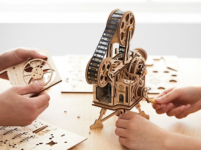 Wooden mechanical model kit being assembled with hands on a light background 3D Puzzle for Kids