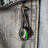 gaffing tape Enamel pin with green, white, and black design on denim fabric