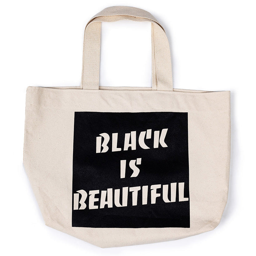 A black and beige cotton tote bag with 'BLACK IS BEAUTIFUL' text printed in bold letters on the side.
