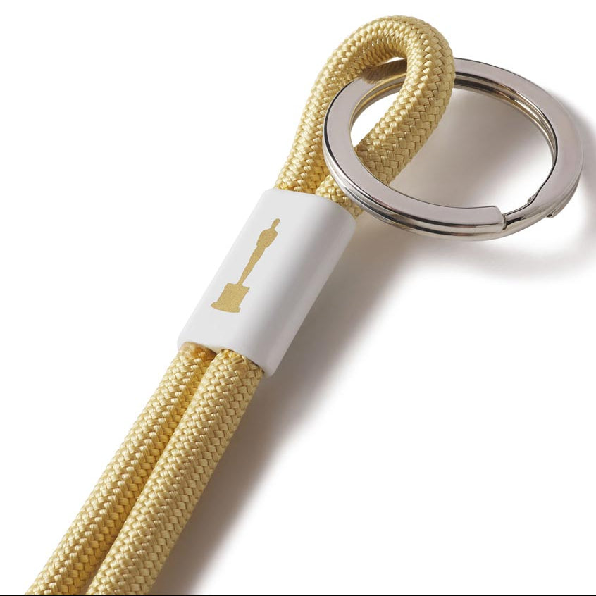 A gold-colored nylon keychain with a metal key loop and a white label with the Pantone logo on it.