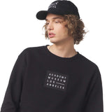Person wearing a black sweatshirt with 'Academy Museum Los Angeles' patch and black cap.