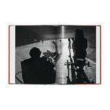 Open book showing a black and white photograph of people in a room with a light source.
