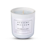 White candle with 'Academy Museum x Flores Lane' label on a white  Indulge in the LOW RESOLUTION CANDLE, an 8oz soy candle featuring leather and smoked cognac scents. 40 hours of eco-friendly luxury in a recycled glass vessel.background FLORES LANE MOVIE GENRE SCENTED CANDLE: FILM NOIR | ACADEMY MUSEUM