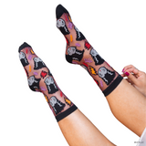 Person wearing black socks with colorful ghost designs on a white background