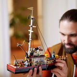 Man holding a detailed model of a ship Orca from the movie Jaws made from building blocks indoors. Jaws (1975) 50th Anniversary Lego Set