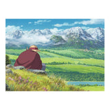 Person sitting on a rock overlooking a scenic landscape with mountains and a lake.
