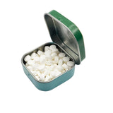 Small open tin filled with white tablets on a white background. Experience the refreshing taste of Jane Austen's Pride and Peppermints! These charming mints are ideal for a quick pick-me-up anytime, anywhere.