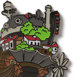 Enamel pin with a design of a steam locomotive, houses, and trees on a white background the castle from the Studio Ghibli film Howls Moving Castle