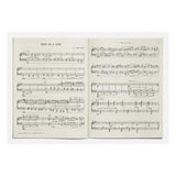 Open sheet music book with musical notation on a white background