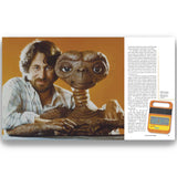 a young Steven Spielberg standing with his arm around E.T. on an orange background