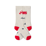 Beige socks with red accents and 'JAWS' logo on a white background. JAWS 50th ANNIVERSARY | ACADEMY MUSEUM