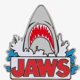 Shark-themed 'JAWS' logo with a silver shark and red mouth on a white background. Closeup image of the lapel pin . JAWS 50th anniversary merchandise at the Academy Museum