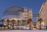 Academy Museum of Motion Pictures at night with palm trees and a clear sky.