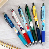Set of colorful pens with character designs on a light wooden surface