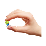 Hand holding a small green alien figurine against a white background