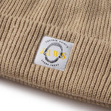 Beige knit beanie with a 'Jaws' logo tag on a white background