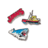 Three enamel pins featuring 'JAWS' text, a boat, and a shark on a white background.