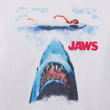 Vintage 'Jaws' movie poster with a shark and swimmer in the water. Closeup of the print of Youth sized tshirt for kids featuring JAWS for the 50th Anniversary of the movie