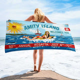 Woman holding a jaws beach towel standing on the beach. Celebrate 50 years of Jaws with the Amity Island Beach Towel! Soft, absorbent, and vibrant, it's perfect for beach days or poolside relaxation.