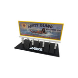 Model of a 'Jaws' sign with 'Amity Island Welcomes You' text and a person in the water, on a white JAWS50th anniversary prop replica 