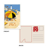 Jaws movie poster with beach scene and 'Jaws 50' anniversary postcard on white background. Officially Licensed JAWS (1975) Artist Edition Postcards by Mondo. Featuring a holiday beach scene from the movie. 