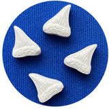 Four white shark fins on a blue textured background. Get ready for a sweet adventure with JAWS Amity Island Sours! Enjoy sour shark tooth candies in a collectible tin that celebrates the iconic Jaws movie.