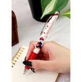 Hand holding a red and white pen with character design, placed on a notebook. Studio Ghibli's Kiki's Delivery Service Pen