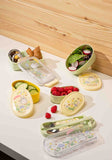 Set of lunch containers with food on a wooden surface. Discover the My Neighbor Totoro Utensil Set (Flower Field) – a charming, officially licensed collection featuring chopsticks, spoon, fork, and a durable case!