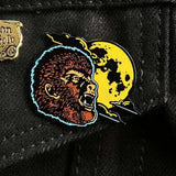 Pin with a wolfman head and moon design on a black background