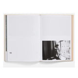 Open book showing a black and white photo of a person sitting by a window.